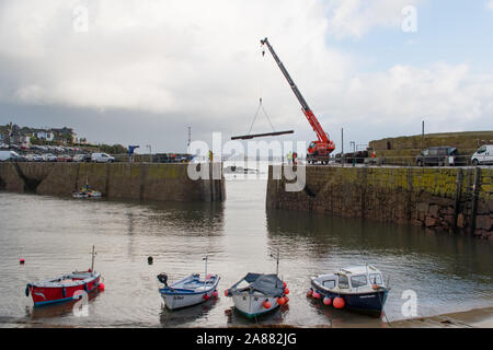 Mousehole, Cornwall, Regno Unito, 7 novembre 2019. Regno Unito Meteo. Ogni anno giant degli spessori di legno vengono abbassati delicatamente nell'apertura di Mousehole Harbour, per proteggerlo dalle tempeste invernali. Visto in background St Michaels Mount a Marazion. Simon credito Maycock / Alamy Live News. Foto Stock