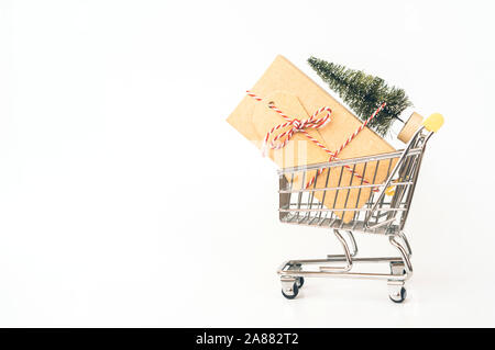 Carrello metallico per lo shopping con un grande regalo, albero di Natale artificiale. Foto Stock