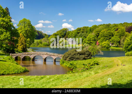 Guardando attraverso il lago con il suo ponte palladiano verso il Pantheon a giardini Stourhead, Wiltshire, Inghilterra, Regno Unito Foto Stock