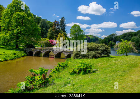 Guardando attraverso il lago con il suo ponte palladiano verso il Pantheon a giardini Stourhead, Wiltshire, Inghilterra, Regno Unito Foto Stock