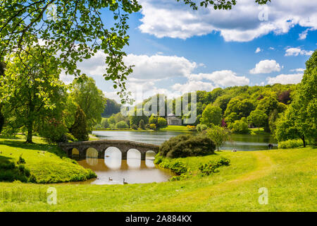 Guardando attraverso il lago con il suo ponte palladiano verso il Pantheon a giardini Stourhead, Wiltshire, Inghilterra, Regno Unito Foto Stock