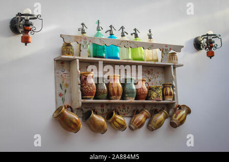 Ripiano decorativo con antichi sifone soda bottiglie e tazze di ceramica sulla parete in cucina in Serbia Foto Stock