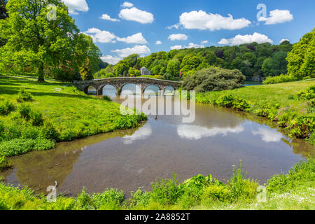 Guardando attraverso il lago con il suo ponte palladiano verso il Pantheon a giardini Stourhead, Wiltshire, Inghilterra, Regno Unito Foto Stock