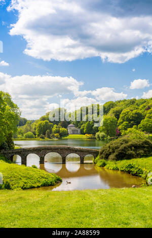 Guardando attraverso il lago con il suo ponte palladiano verso il Pantheon a giardini Stourhead, Wiltshire, Inghilterra, Regno Unito Foto Stock