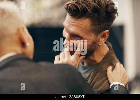 Felice giovane uomo che parla di donna matura e sorridente durante il loro incontro Foto Stock