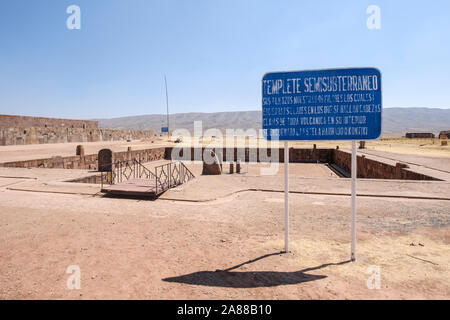 Semi-tempio sotterraneo cartello con il tempio di Kalasasaya parete in background a Tiwanaku complesso archeologico, Bolivia Foto Stock