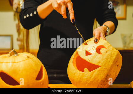 Il carving zucche di Halloween in cucina. Marcatura e carving grande Jack o'zucca lanterna Foto Stock