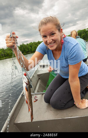 Una giovane donna mostra una trota arcobaleno catturati nel lago di trote nel Northwoods villaggio di Boulder Junction, Wisconsin. Foto Stock