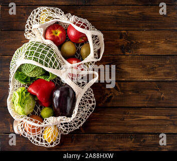 Frutta e verdura in sacchetti di netto su scuro dello sfondo rustico Foto Stock