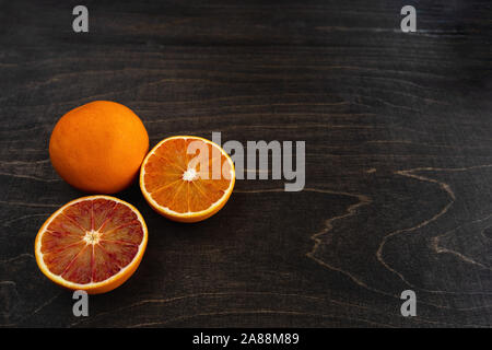 Un primo piano della vibrante sangue organica arance su sfondo scuro con copia spazio. Foto Stock
