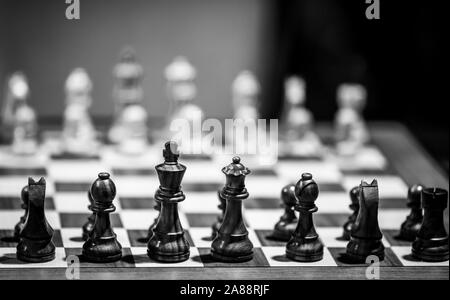 Monocromatico profondità di campo (messa a fuoco selettiva) immagine con scacchi in legno pezzi su un tavolo di legno prima di un concorso professionale. Foto Stock