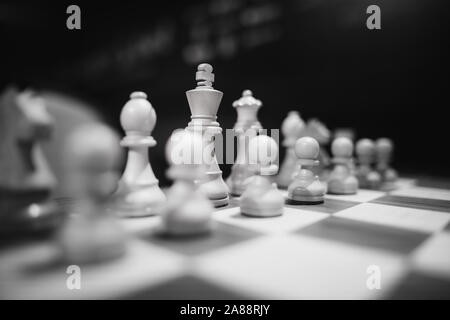 Monocromatico profondità di campo (messa a fuoco selettiva) immagine con scacchi in legno pezzi su un tavolo di legno prima di un concorso professionale. Foto Stock