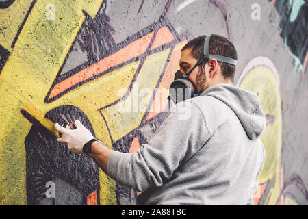 Street Graffiti artist pittura con un colore spray può un graffiti sul muro della città - Urban, Lifestyle Arte di strada Nozione Foto Stock