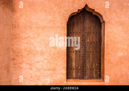 Il Marocco, Marrakech. Giardini di Menara. Dettagli architettonici su una porta di legno su una parete in ocra. Foto Stock