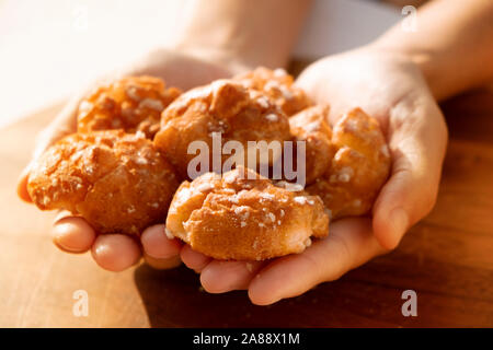 Primo piano di un uomo caucasico con alcuni chouquettes, dolci tipici della Francia, nelle sue mani Foto Stock