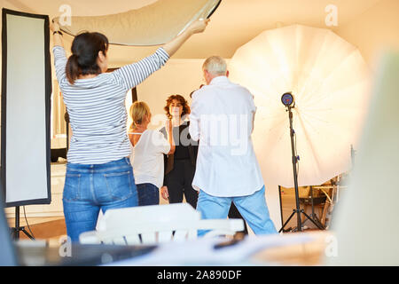 Fotografo team con il modello e make-up artist nella foto di studio durante il servizio fotografico Foto Stock