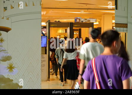 Bangkok, Tailandia - 8 Novembre 2019 : sfocato il movimento di persone in fila a piedi attraverso il rivelatore di metalli in entrata del Siam Paragon Shopping Mall Foto Stock