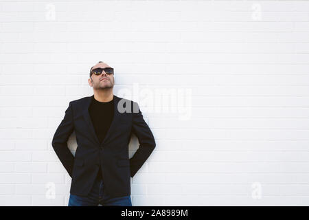 Uomo che indossa occhiali da sole e blazer da parete bianca Foto Stock