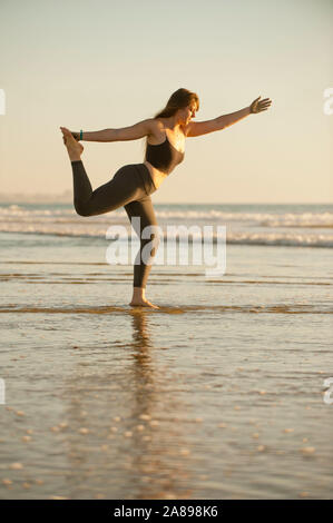 Giovane donna fare yoga sulla spiaggia Foto Stock