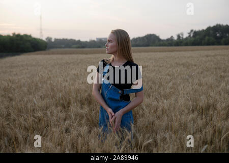 Giovane donna che indossa tute in campo di grano Foto Stock