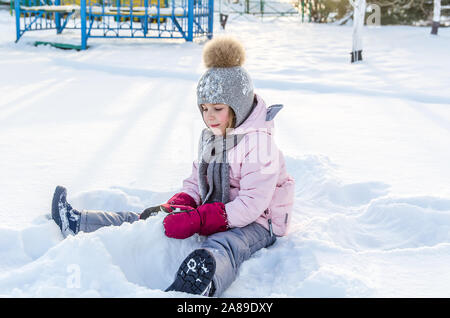 Carino bambina gioca con la neve in inverno. Angelo d'inverno Foto Stock