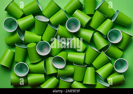 In plastica verde stoviglie monouso, come ad esempio un sacco di tazze sullo sfondo verde con copia spazio. Il concetto di utensile per picnic. Utilizzata anche in un fast food r Foto Stock