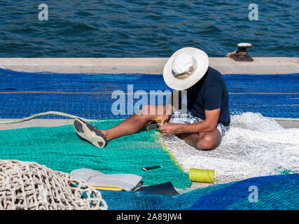 Le reti da pesca stabiliti in banchina con una persona riassettavano le reti al famoso resort di Maiorca di Port d'Andratx. Foto Stock