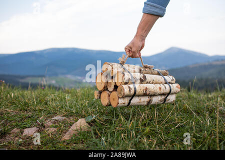 L'uomo traveler mani tenendo la legna per il fuoco in montagna. luogo di iscrizione Foto Stock