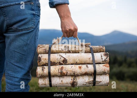 L'uomo traveler mani tenendo la legna per il fuoco in montagna. luogo di iscrizione Foto Stock