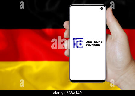 Il logo della società pubblica Deutsche Wohnen AG visualizzata su uno smartphone. Bandiera della Germania sfondo. Credito: PIXDUCE Foto Stock