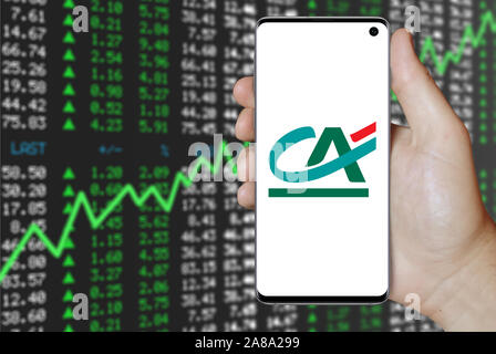 Il logo della società pubblica Crédit Agricole visualizzato su uno smartphone. Positivo del mercato azionario sfondo. Credito: PIXDUCE Foto Stock
