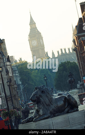 Trafalgar Square lions guardia sotto una vista nebbiosa di Big Ben all'orizzonte Foto Stock