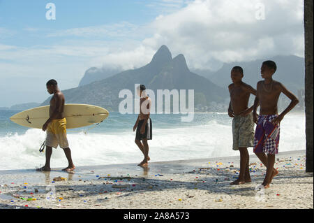 RIO DE JANEIRO - MARZO 16, 2011: giovane brasiliano surfer passeggiate sul lungomare di Ipanema di trasportare una tavola da surf sopra le onde del mare a Arpoador. Foto Stock