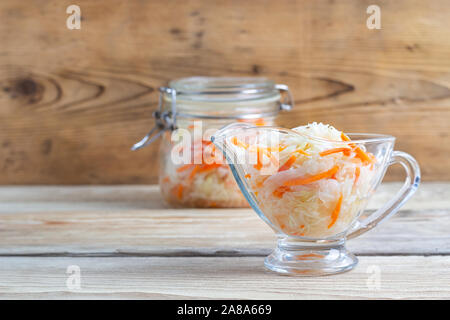 Cavolo fermentato in vasi di piastra su una tavola di legno Foto Stock