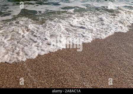 Foro di marea. Un'onda viene eseguito su di una spiaggia di sabbia. Mare d'autunno. Sea Wave. Ciottoli Foto Stock