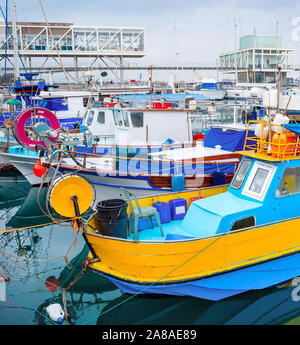 Coloratissime barche di pescatori ormeggiate nel porto di Limassol con ristoranti sul molo, Cipro Foto Stock