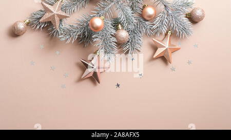 Vista superiore albero di Natale ramo con color rame stelle e le sfere su sfondo beige con glitter coriandoli. Xmas minimo piatto stile laici composizione, Foto Stock