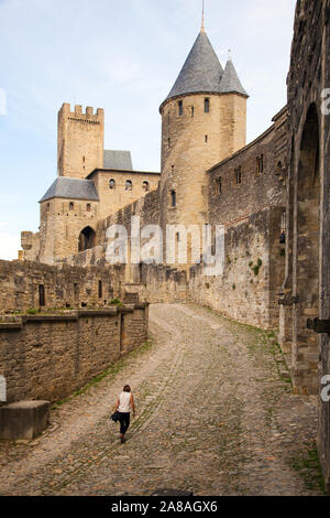 Donna che cammina intorno alla collina del castello medievale in cittadella fortificata città francese città di Carcassonne nella regione Languedoc di Francia Foto Stock