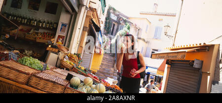 Giovane donna odorare un melone in un mercato, Saint Tropez, Francia Foto Stock