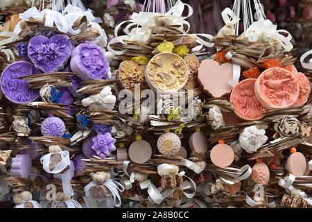 Extreme close up di cuore aromatico, di fiori e di forma rotonda saponi per una corda decorata con nastri e pizzi. Iconico Europeo Orientale souvenir. Foto Stock