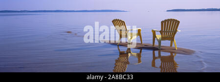 La riflessione di due sedie adirondack in un lago, il lago Michigan, Michigan, Stati Uniti d'America Foto Stock