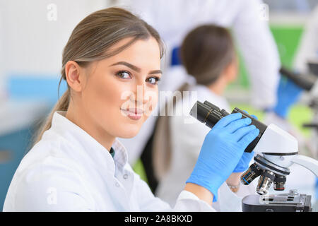 Un gruppo di giovani scienziati di laboratorio lavora presso il laboratorio con provette e microscopio, di test o di ricerca in laboratorio clinico. Donna scienziato cerca Foto Stock