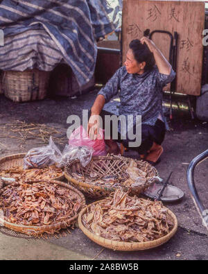 Cheung Chau Isola, Cina. 30 ott 1981. Un seduto donna cinese ordina i pezzi di pesce essiccati in cesti di vimini in Cheung Chau village. Tradizionalmente un villaggio di pescatori, l'isola, 6.2 miglia (10 km) con il traghetto da Hong Kong, è diventata una delle principali attrazioni turistiche. Credito: Arnold Drapkin/ZUMA filo/Alamy Live News Foto Stock