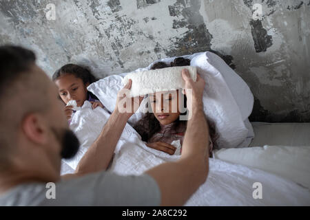 Padre amorevole mettendo un asciugamano freddo sul fronte della figlia Foto Stock