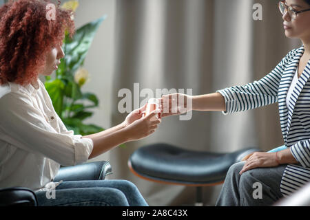Ricci i capelli rossi donna prendendo sonniferi da psicologo Foto Stock
