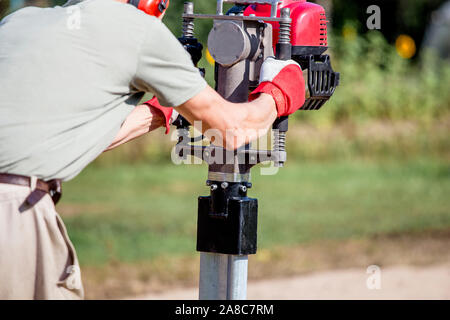 Uomo che utilizza un utensile manuale per l'espansione di pali a benzina all'aperto sul cantiere. Foto Stock