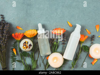 Organici vegetali cosmetici a base di concetto. Vista dall'alto di erbe varie piante e bellezza contenitori per prodotti vintage su sfondo blu. Foto Stock