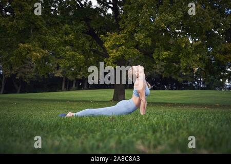 Giovane donna fare yoga nel parco, ginnastica, Olympiapark, Monaco di Baviera, Germania Foto Stock