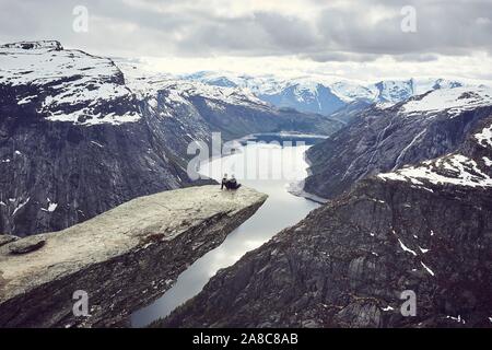 Paar siede su una piattaforma rocciosa su Trolltunga e si affaccia sul fiordo paesaggio, Trollzunge, vicino a Odda, provincia Hordaland, Vestland, Norvegia Foto Stock