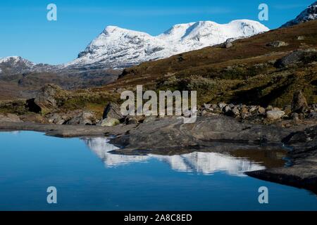 Okstindan mountain range, anche Okstindene, con ghiacciaio Okstindbreen, acqua riflessione nel piccolo lago di montagna, Nordland, Norvegia Foto Stock